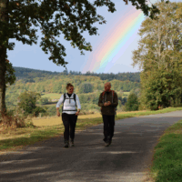 Lentewandelen onder een regenboog Een man en een vrouw wandelen in de groene omgeving in de Morvan onder een regenboog